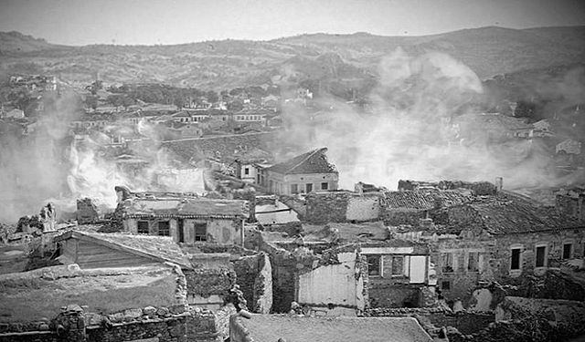 A black and white photo of a town with smoke coming out of it
Description automatically generated with low confidence
