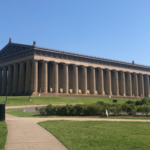 Parthenon with columns and grass Description automatically generated